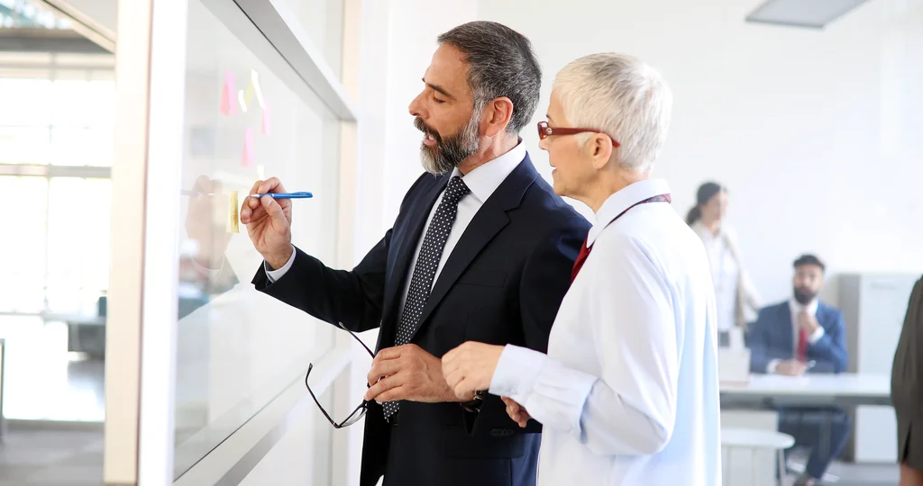 IT-Experte und Arzt analysieren gemeinsam einen Praxis-Workflow am Whiteboard